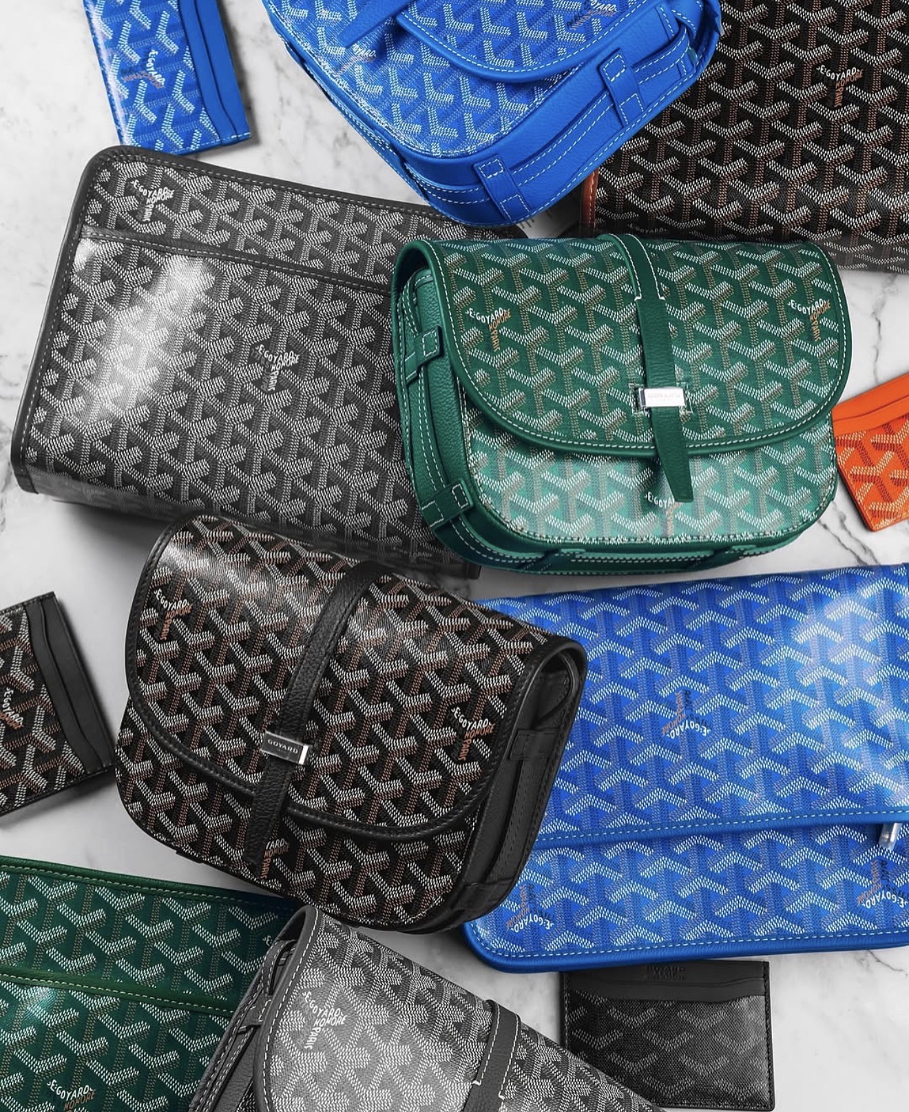 A selection of designer bags and small leather goods arranged on a marble surface